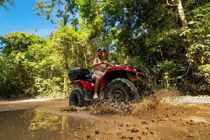 Rider on a red ATV splashing through mud on a jungle ATV tour from Playa del Carmen, Mexico
