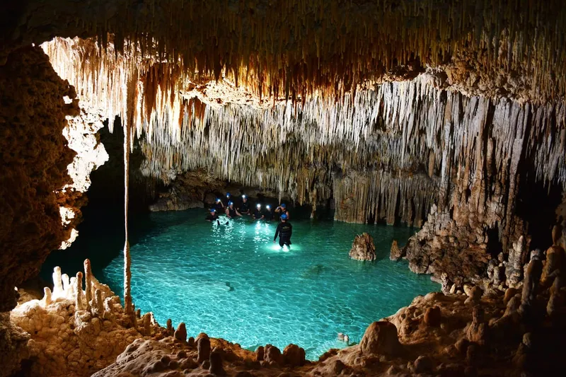 Guided group wading through a lit underground cavern at Río Secreto on a tour from Playa del Carmen, Mexico